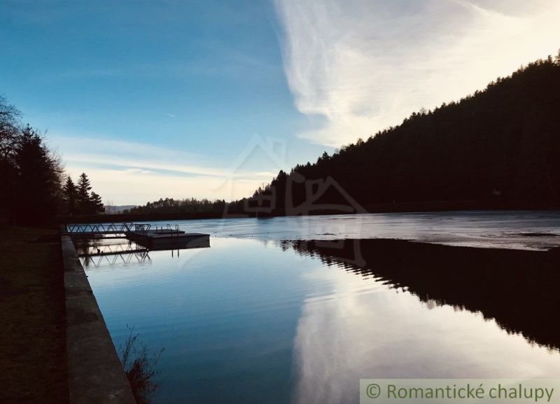 A view of the lake's surface in Štiavnické Bane near a family house with a reflection of the forest.