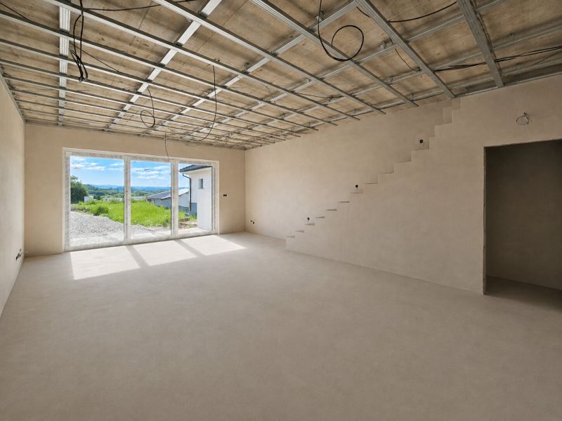 A spacious room in a 5 or more bedroom apartment with a staircase and large windows.