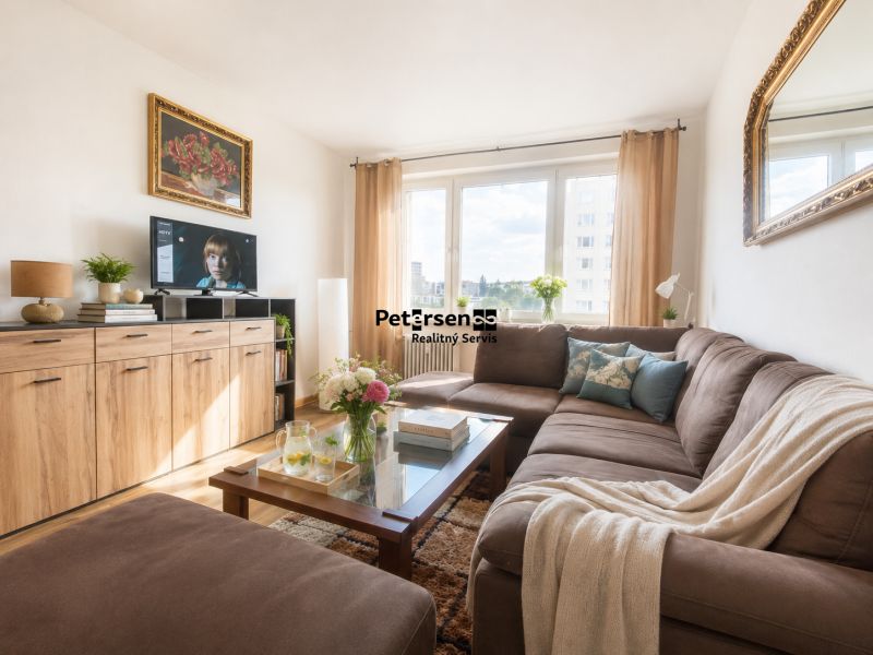 Living room in a 3-room apartment with a dark sofa and a large window.