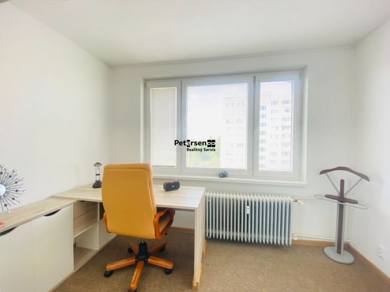 A study in a 3-room apartment with a window and a chair on a carpeted floor.