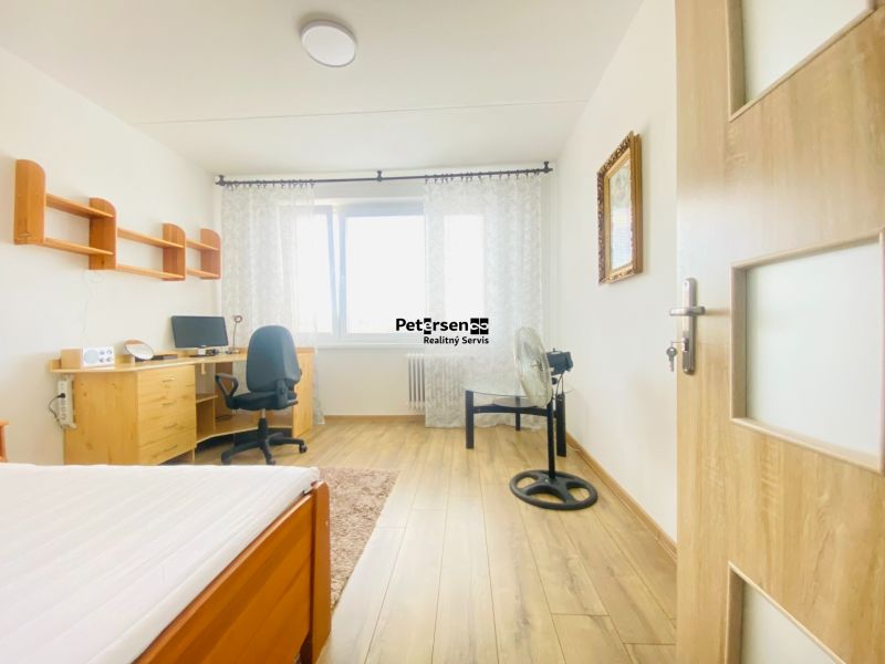 The interior of a room in a 3-room apartment with a wooden decor floor and a desk.