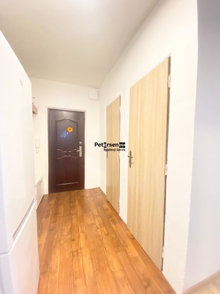 A hallway in a 3-room apartment with a wooden decor floor and multiple doors.