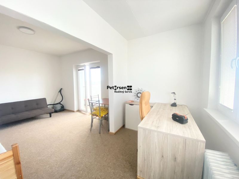 A workspace with a desk, sofa, and balcony door in a 3-room apartment.