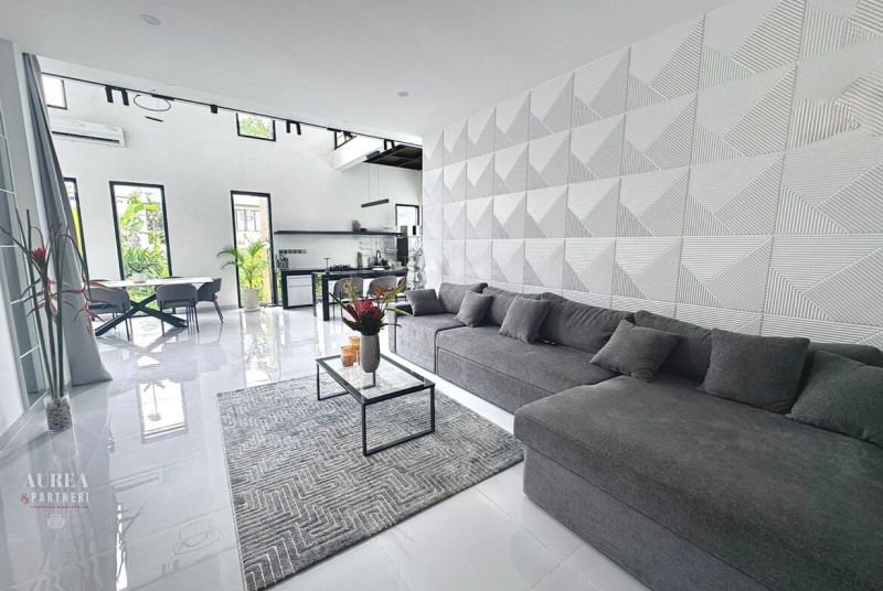 Interior of a villa with a comfortable gray sofa, geometric walls, and an open space.
