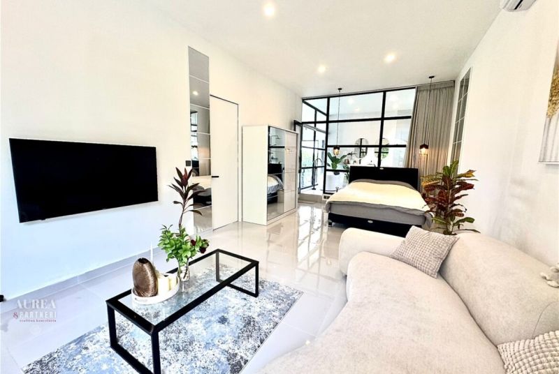 Living room of the villa with white furniture, plants, and a glass wall.
