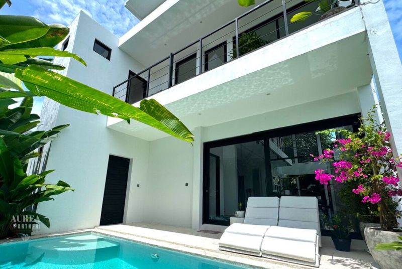 Bali villa with a pool and terrace, surrounded by greenery and flowers.