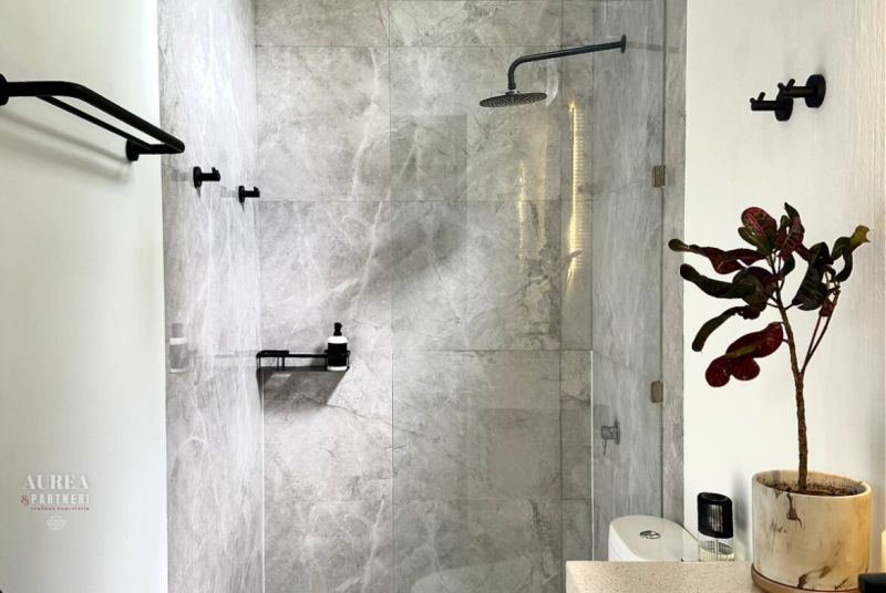 Bathroom in a villa with a plant, shower, and marble tiles.