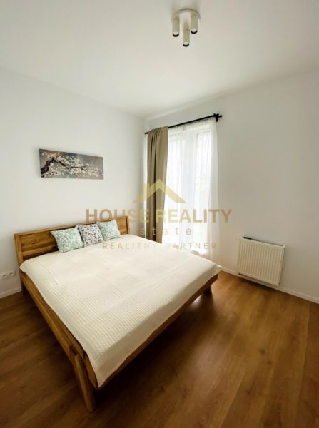A room in a 2-room apartment with a double bed and a wooden decor floor.