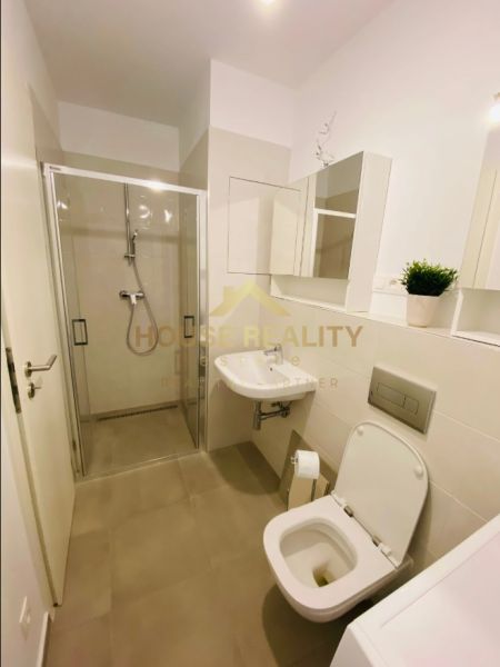 Bathroom with toilet, shower, and sink in a 2-room apartment.