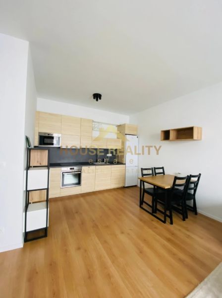 The kitchen of a two-room apartment with a wooden decor on the floor and a dining table.