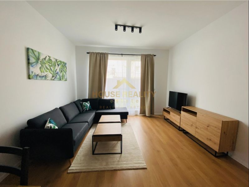 Living room in a two-room apartment with a wooden decor floor and a comfortable sofa.