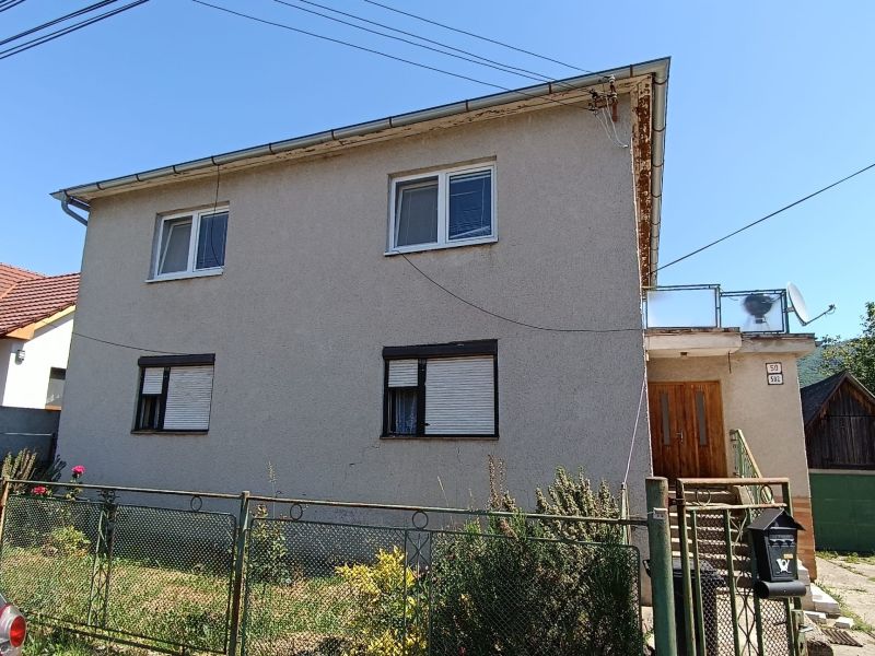 A family house in Nová Baňa with a simple facade, metal fence, and garden.