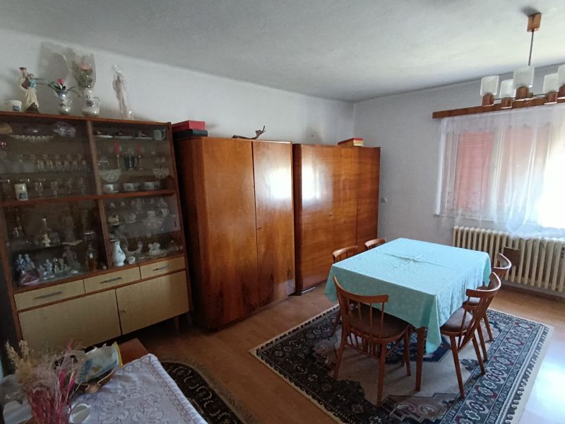 Dining room in a family house with cabinets, a display case, and a carpet on a floor with a wooden decor.