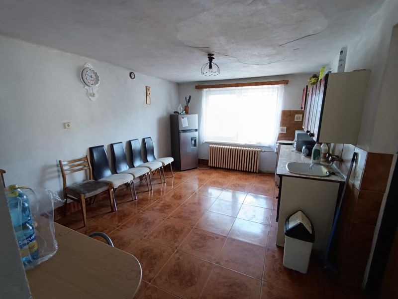 A kitchen in a family house with a brown floor, chairs, and kitchen units.