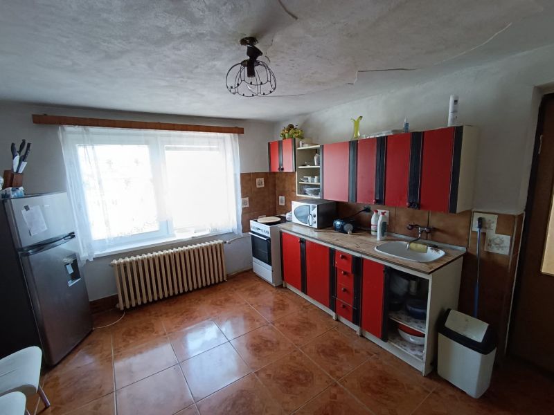 A kitchen with red cabinets, tiled floor, and appliances in a family house.
