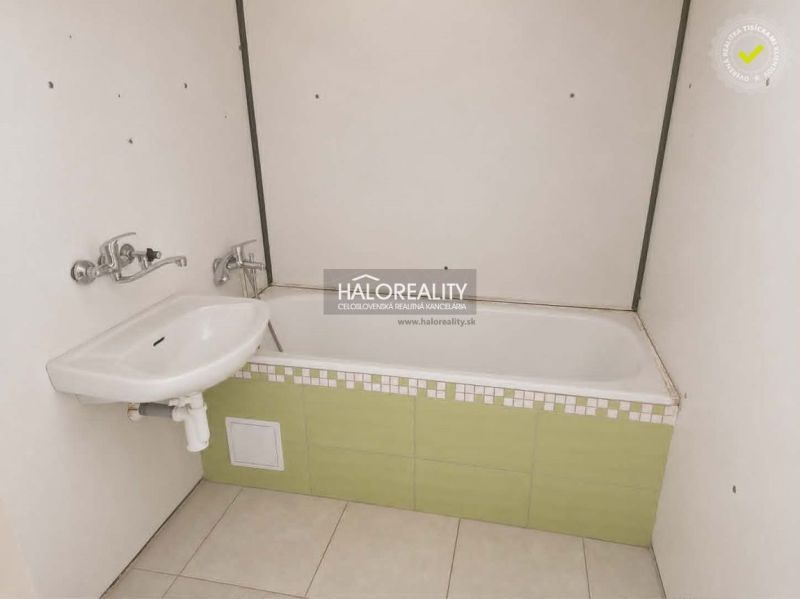 A bathroom in a studio apartment with a bathtub and a sink.