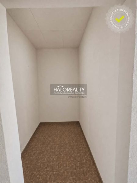 A narrow room with white walls and a floor with a wooden decor in a studio apartment.