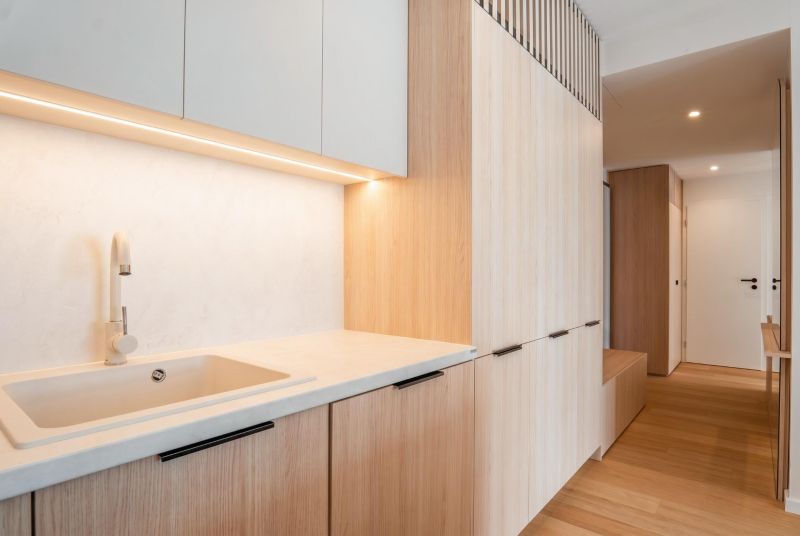A kitchen in a 3-room apartment with a white countertop and a floor with a wood pattern.