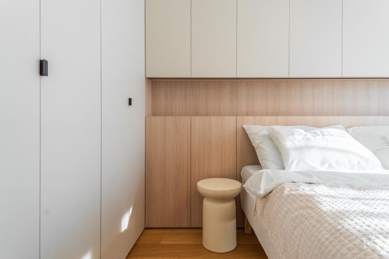 Bedroom with wood-patterned flooring in a 3-room apartment, bed, cabinets, and nightstand.