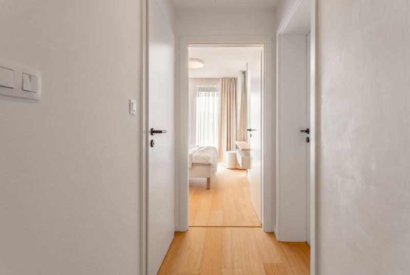 A hallway with white doors and a wooden decor floor in a 3-room apartment.