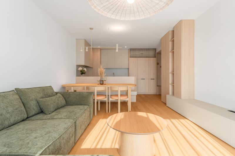 Living room with a sofa, dining table, and wood-patterned flooring in a 3-room apartment.