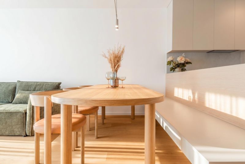 A dining room with a wooden table and chairs in a 3-room apartment, flooring with a wooden decor.