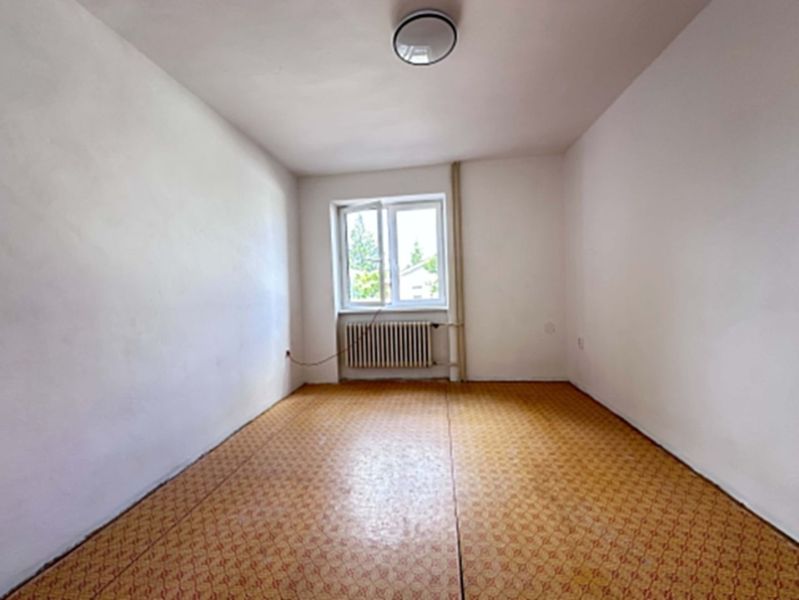 A spacious bright room with a window, wooden decor flooring, family house.
