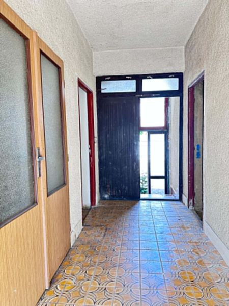 A hallway in a family house with tiles and wooden doors.