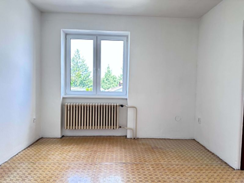 A room in a family house with a window, a radiator, and a floor with a wooden decor.