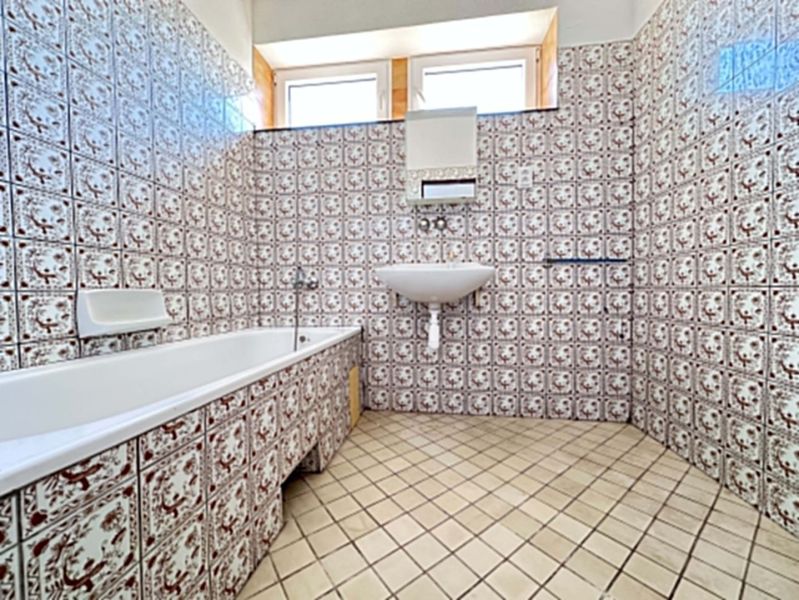 A family house bathroom with retro tiles and a bathtub.