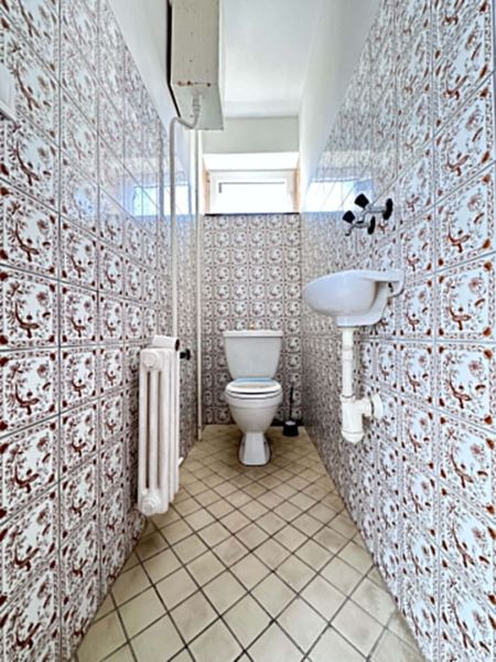 Bathroom in a family house with a toilet, sink, and tiled walls.