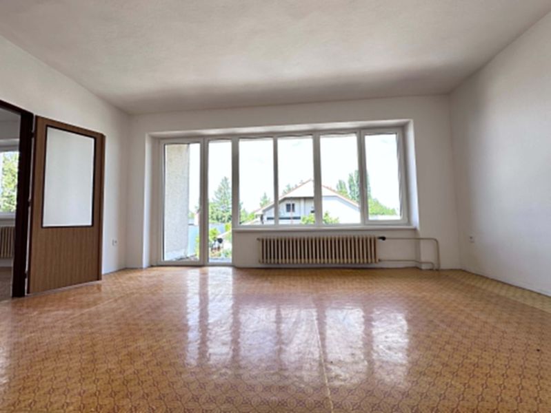 Living room in a family house with a large window and a wooden decor floor.