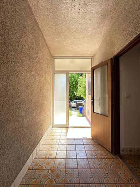 A hallway with decorative tiles leading to illuminated doors in a family house.