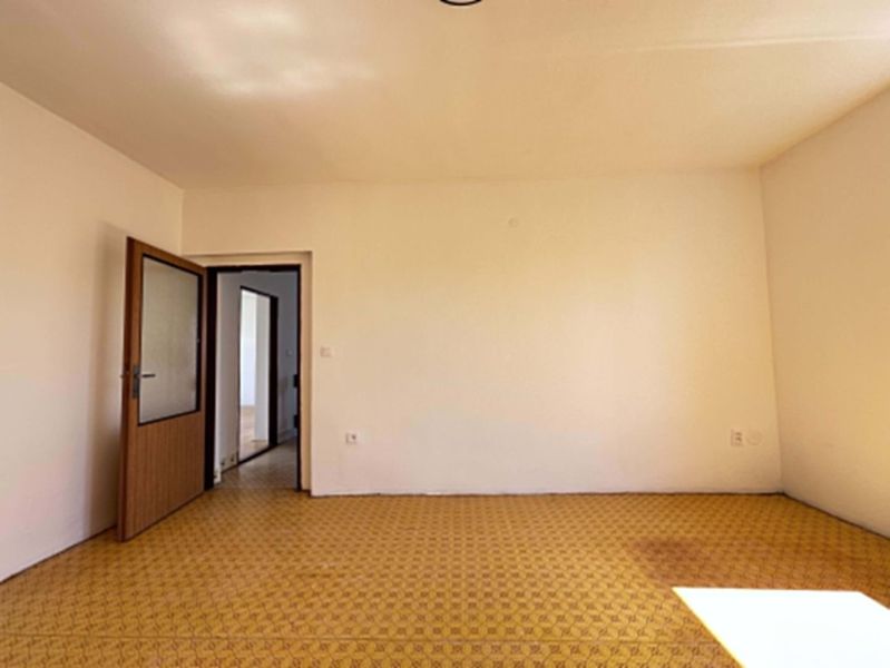 A room in a family house with a carpet and open doors, white walls.