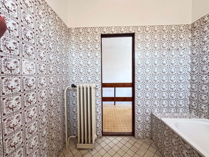 A bathroom in a family house with decorative tiles and a radiator.