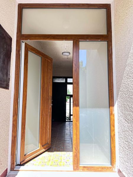 Entrance door with a wood decor leading to a family house, also visible is ceramic tiling.