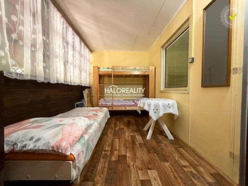 A room in a cabin with a bunk bed, a bed, and a floor with wooden decor.