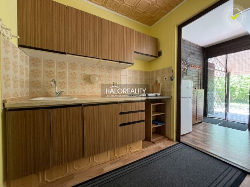 A kitchen in a cottage with a countertop, sink, and a view of the terrace with a wooden decor.
