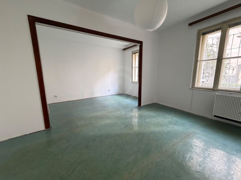 Empty room in a 3-room apartment with large windows and a green floor.