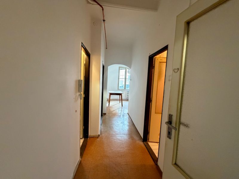 A corridor with white walls and a floor with a wooden decor in a 3-room apartment.