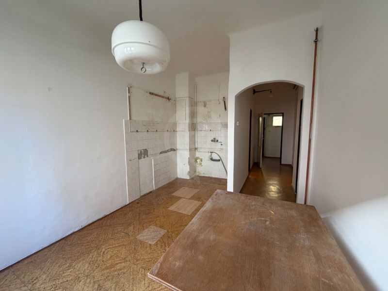 A kitchen in a 3-room apartment with white walls and a floor with a wood decor.