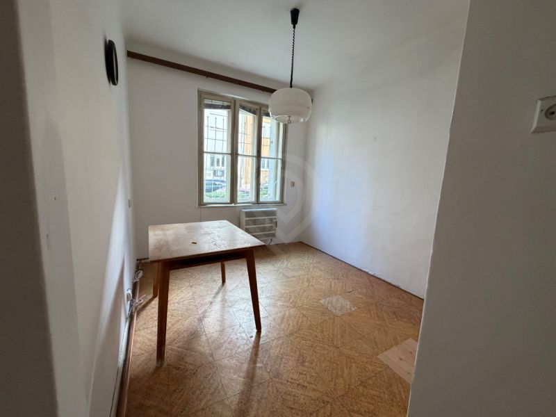 Dining room with wood-patterned flooring in a 3-room apartment, table and chandelier.