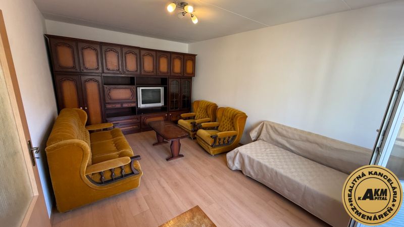 A living room with retro furniture and a wooden decor floor in a studio apartment.
