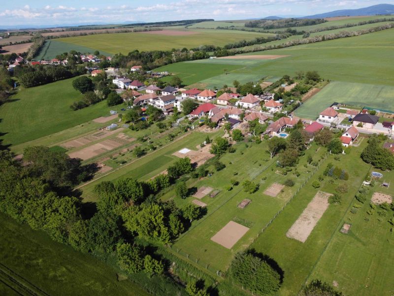 An aerial view of the green gardens in Hruboňovo, surrounded by fields and the village.