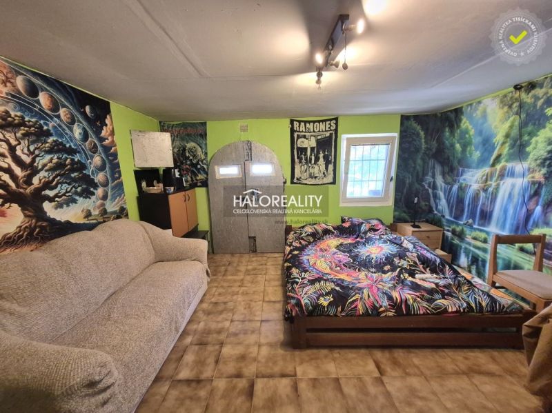 A room with a sofa, bed, striking wall decorations, and a wooden-patterned floor in the Gardens.