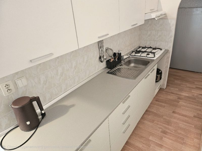 A kitchen in a studio apartment with a wood-patterned floor and a gas stove.