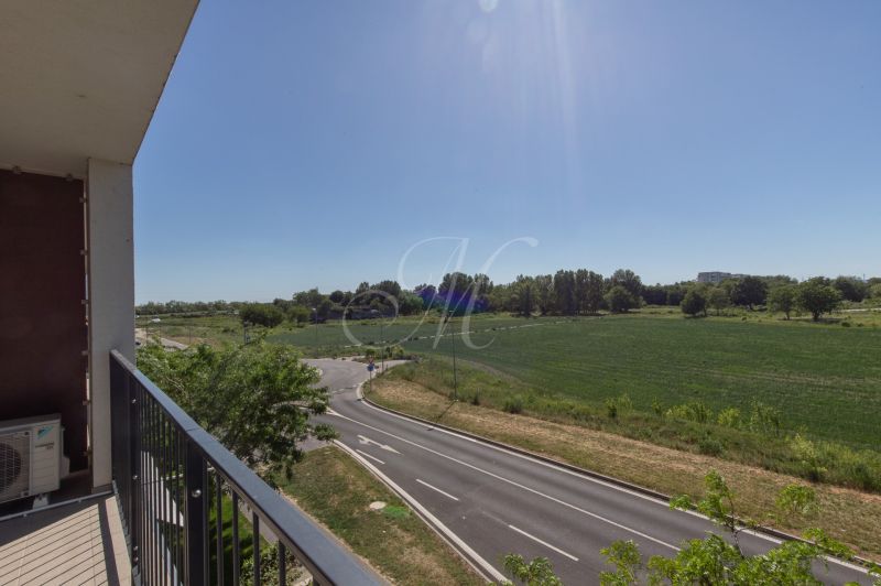 View from the balcony on Zuzana Chalupová Street, Bratislava - Petržalka, with a road and greenery.