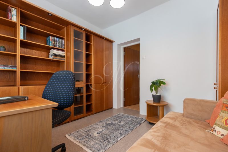 3-room apartment with wooden shelves, a table, and a comfortable armchair.