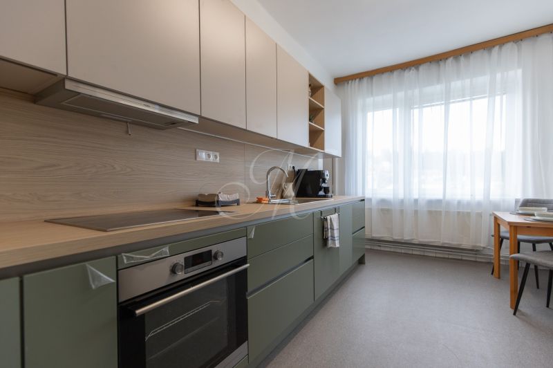A kitchen in a 3-room apartment with modern furniture and natural wooden decor.