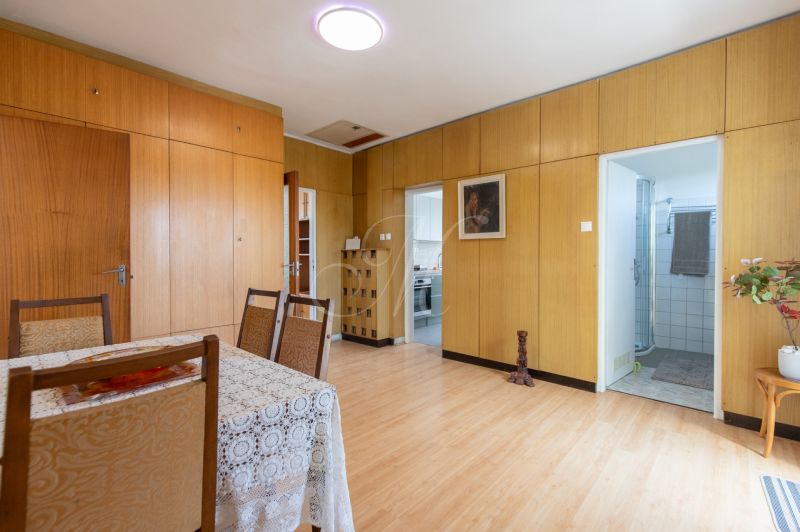 A room with a wooden decor floor, a table, and chairs in a 3-room apartment.